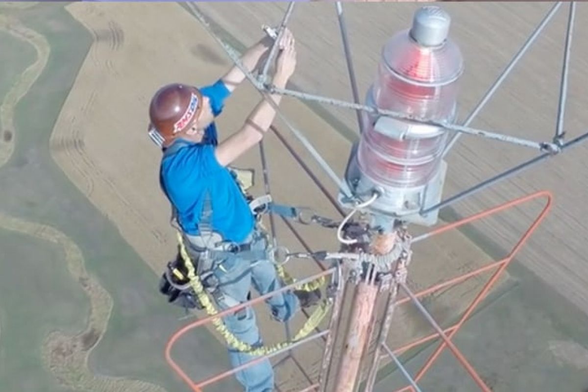 Técnico consertando ma antena de tv digital ilustra nosso artigo sobre A Influência da altura da antena na qualidade do sinal de TV.