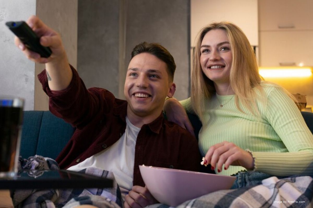 Casal assiste TV em casa enquanto come pipoca ilustra nosso artigo sobre: Durabilidade e qualidade do seu novo controle remoto.