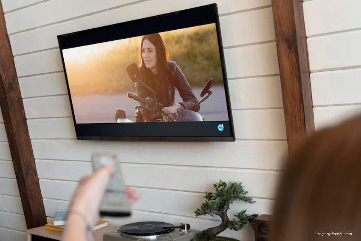 Mulher apontando controle remoto para a TV ilustra nosso artigo sobre: Quais modelos de televisão suportam a Proeletronic TV Box?