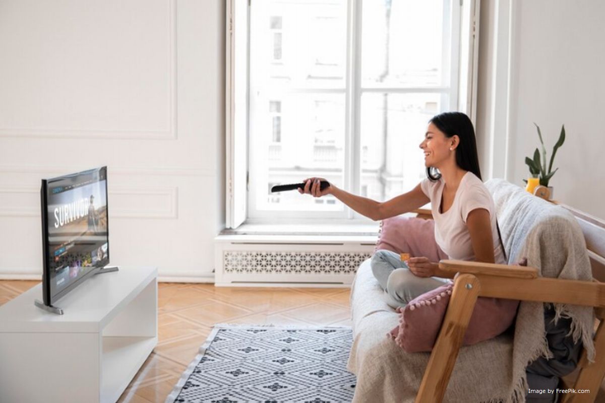 Uma mulher aponta controle remoto para a sua TV box ilustra nosso artigo sobre: Preciso ter internet para usar a TV Box?